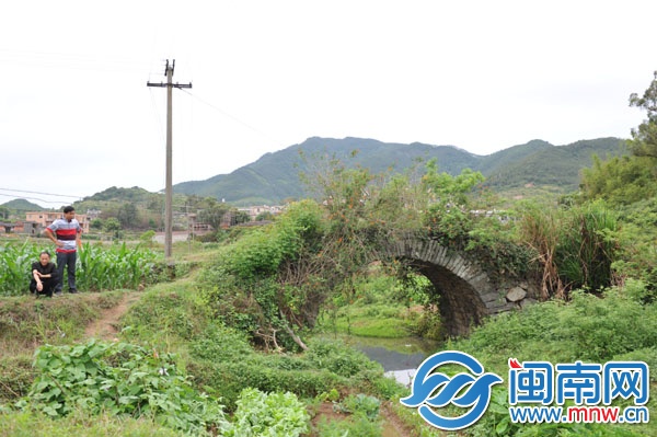 已廢棄的石拱橋，被野草覆蓋，下有溪流，村民稱此路